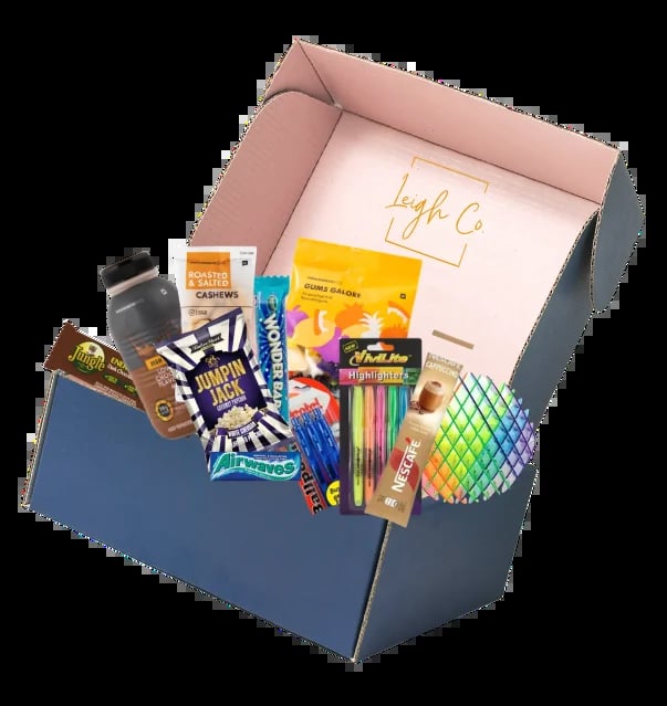 Open gift box with pink lining containing assorted snacks, candy, art supplies, and colorful items labeled with high C branding