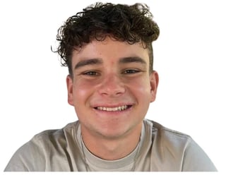 Young man with curly dark hair smiling at camera, wearing a light gray t-shirt against white background